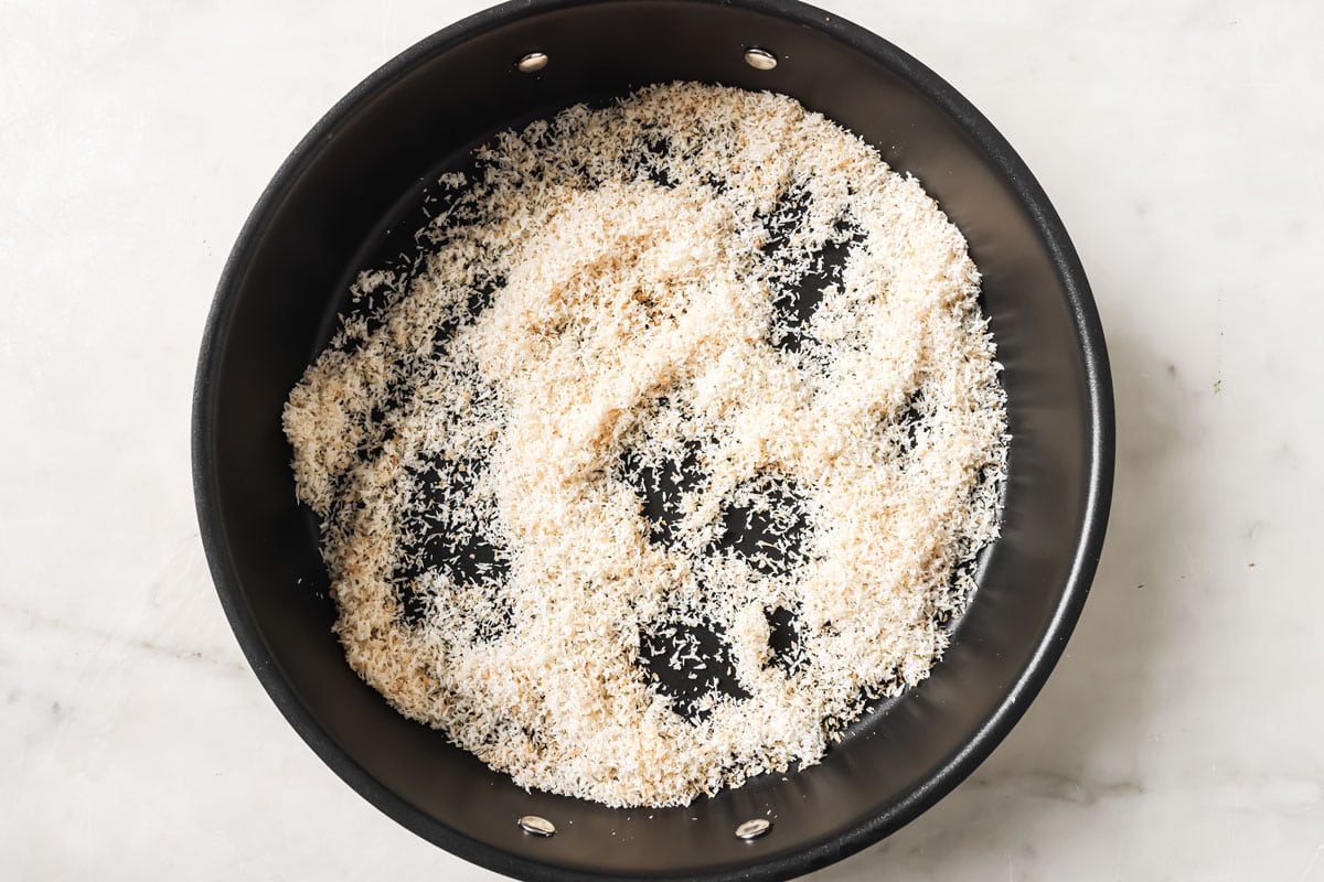 Toasting desiccated coconut in a frying pan.