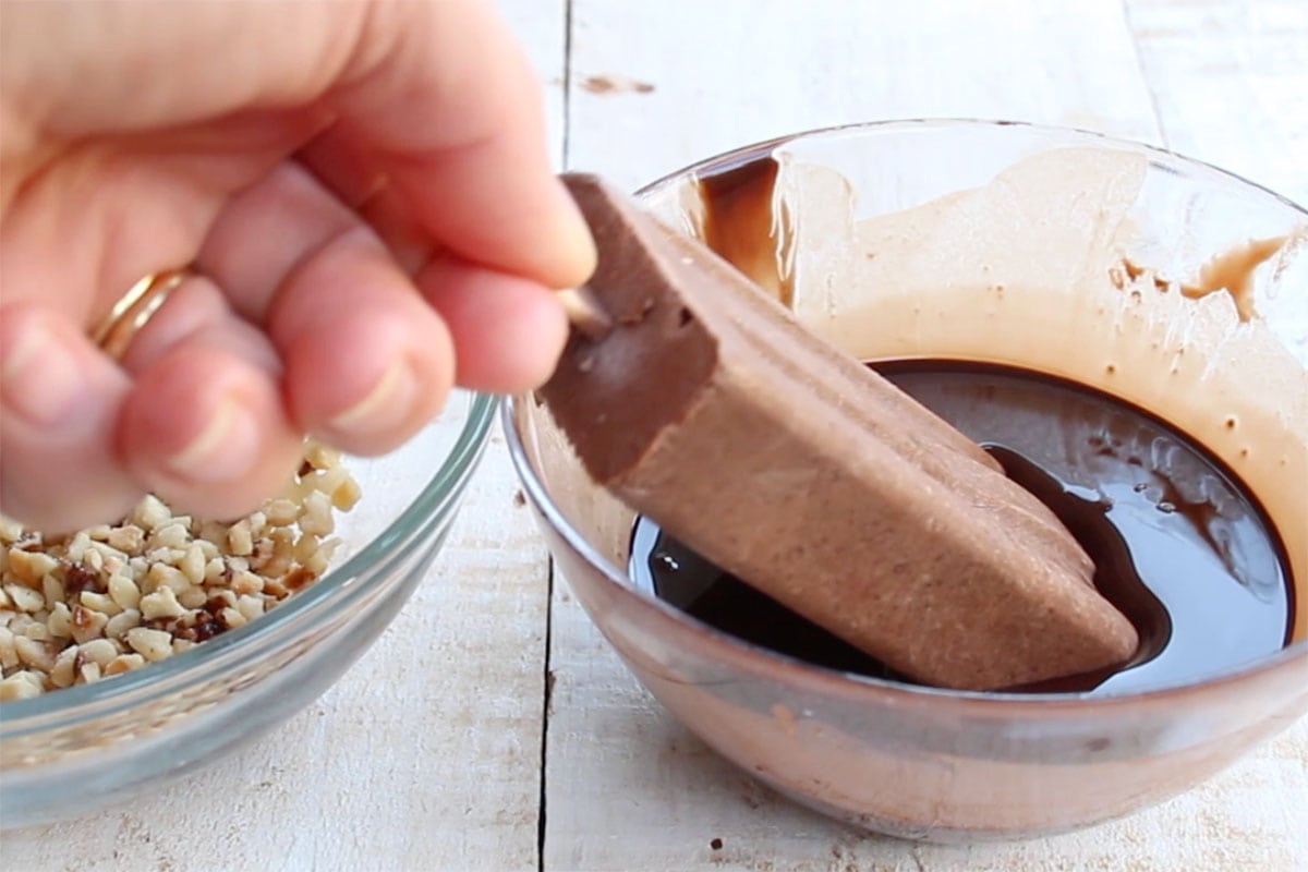Dipping a fudgesicles into melted chocolate.