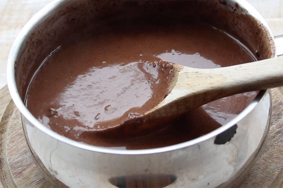 Chocolate mixture in a saucepan and a wooden spoon.