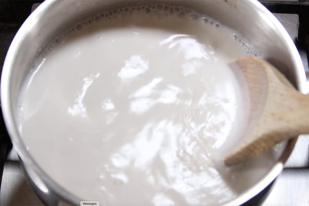 Stirring the coconut cream in a saucepan with a wooden spoon.