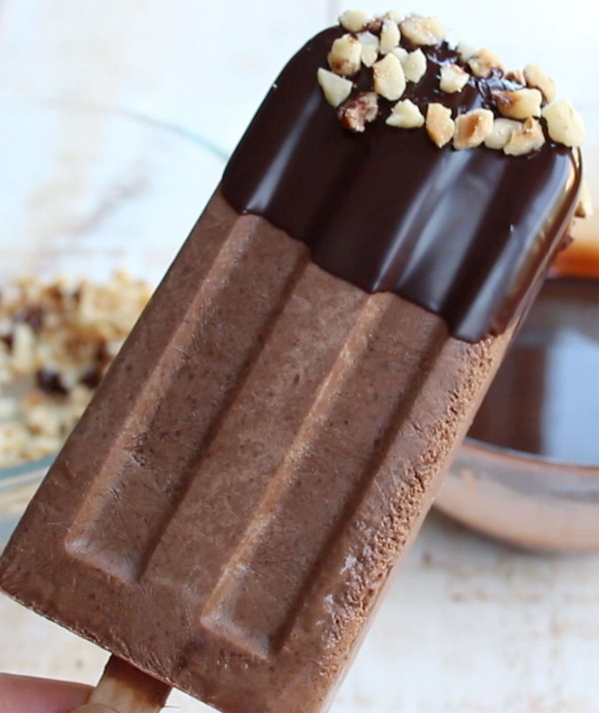 A sugar free chocolate fudgesicles topped with a chocolate coating and crushed hazelnuts.