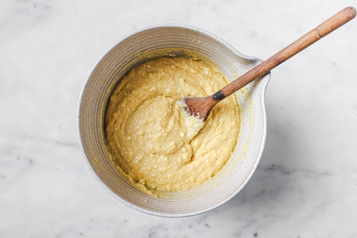 Muffin batter in a large mixing bowl and a wooden spoon.