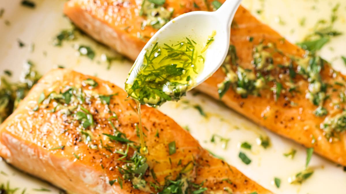 Topping the salmon fillets with an olive oil herb dressing.