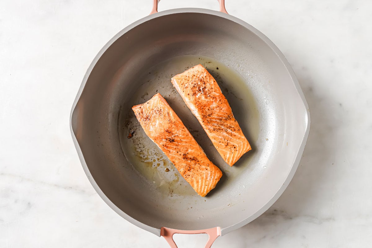 2 salmon fillets skin side down in a frying pan.