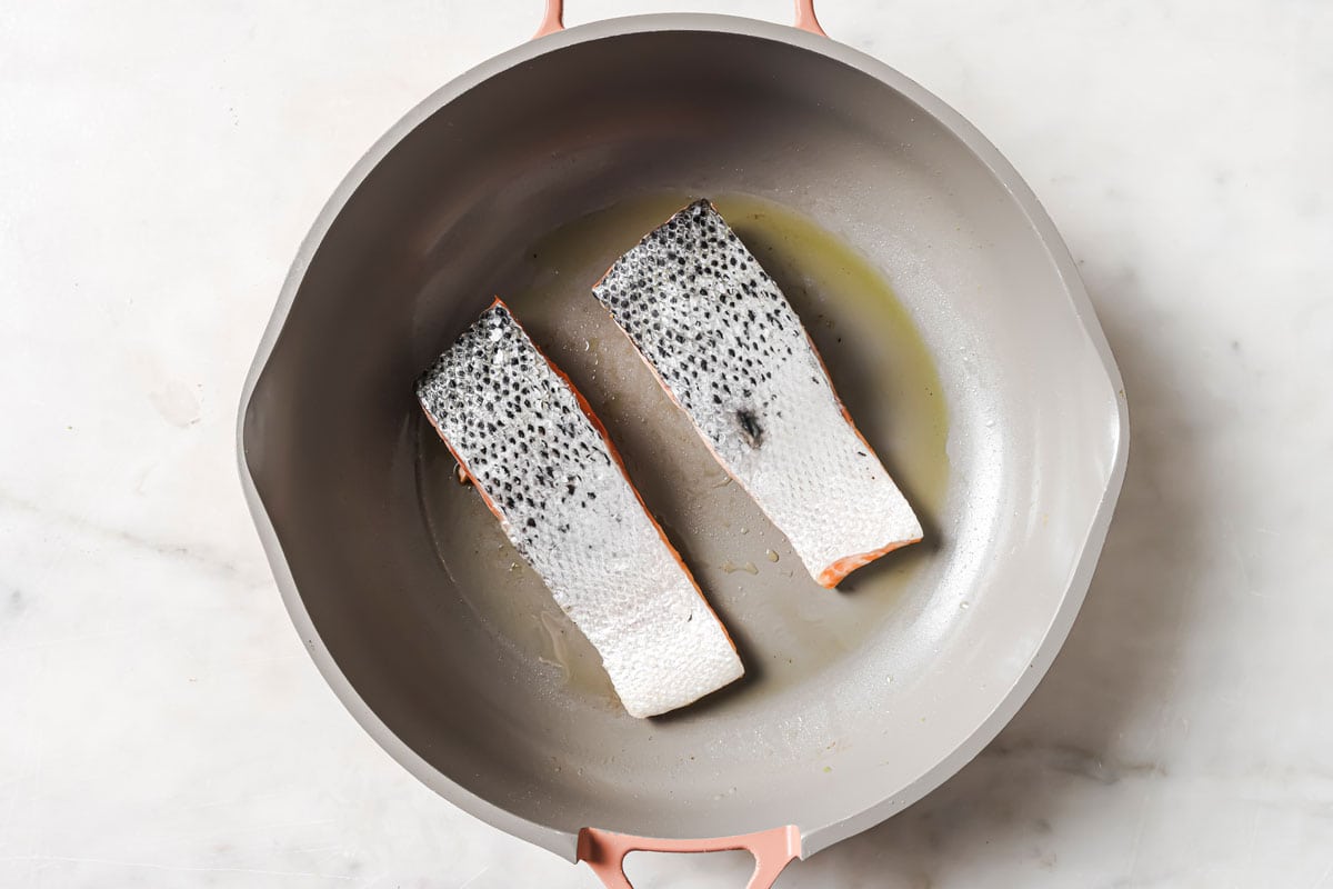 2 salmon slices skin side up in a frying pan.