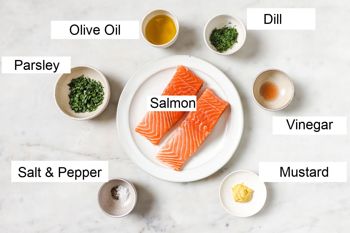 2 salmon fillets on a plate, surrounded with the ingredients to make the dressing, measured into bowls and labelled.