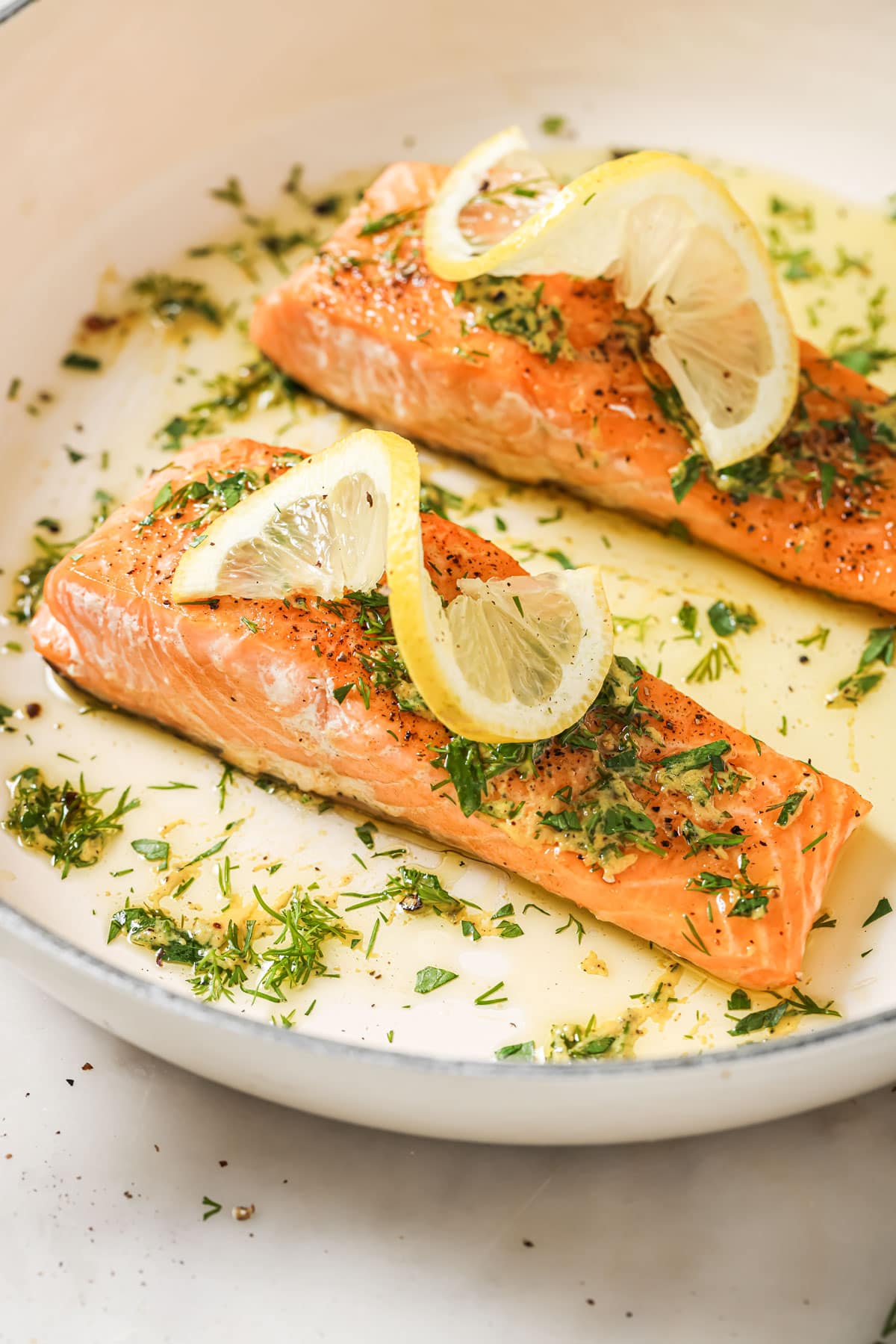 2 salmon fillets topped with dressing and lemon slices.