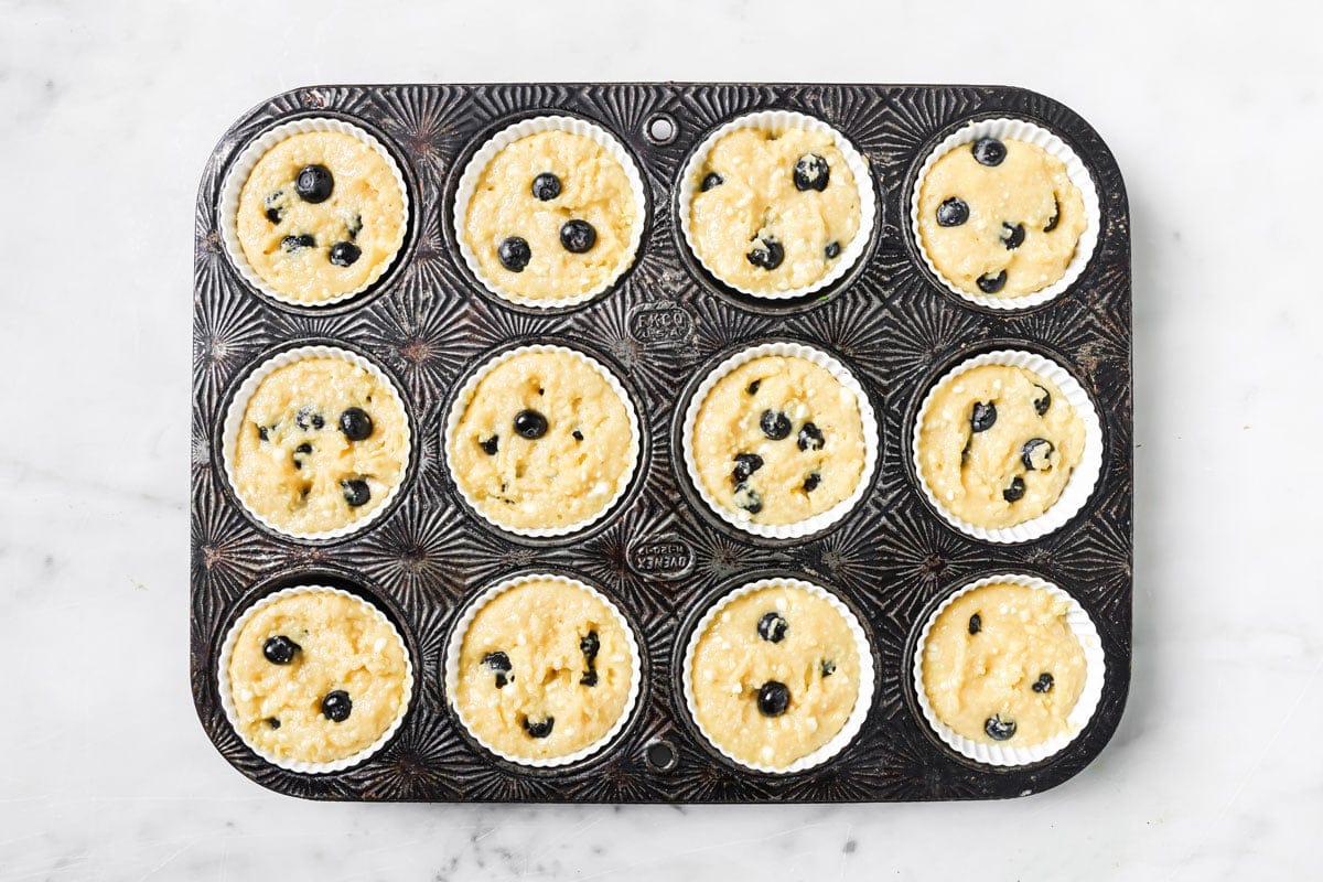 Fresh blueberries, pressed into the muffin batter in a muffin pan.