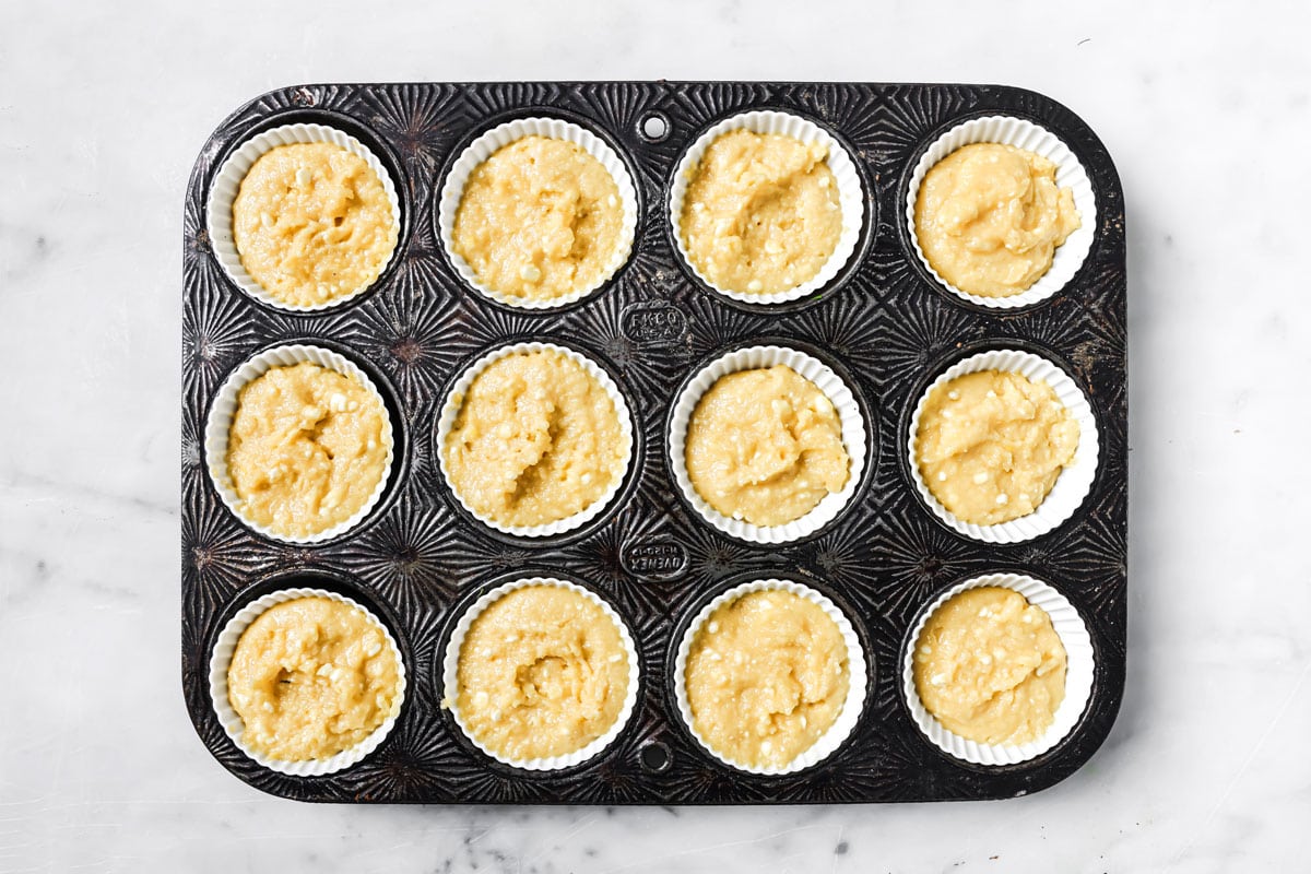 Muffin batter filled into 12 silicone cases in a muffin pan.