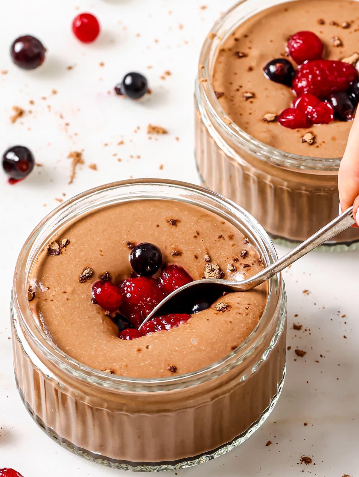 A spoon diving into a bowl with chocolate pudding.