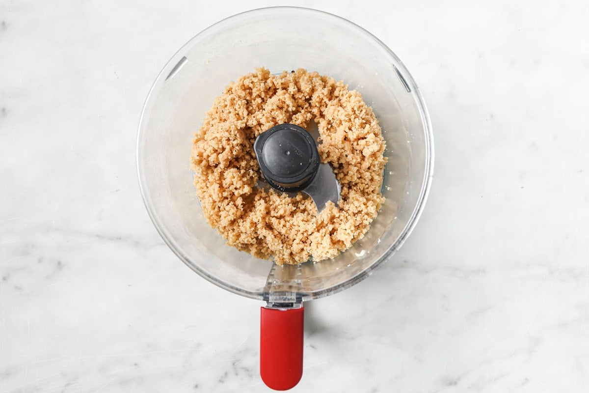 Crumbly dough in a food processor bowl.