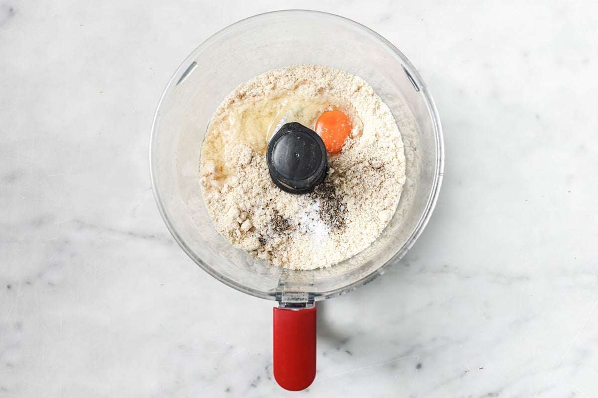 Almond flour ad egg in a food processor bowl.