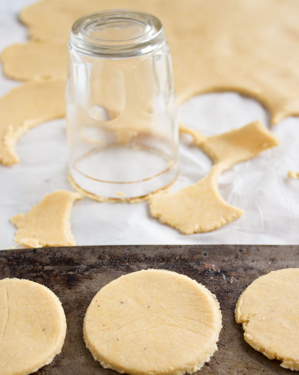 Cutting out round cracker shapes from rolled out dough with a small glass.