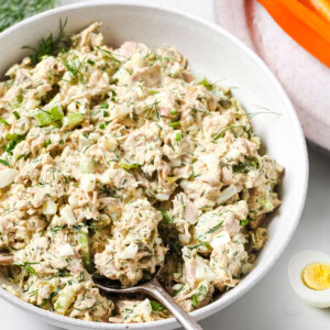 A bowl with tuna egg salad and a spoon.