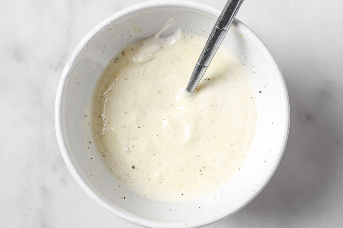 Mayonnaise with additional seasonings in a bowl and a spoon.