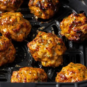 Juicy chicken meatballs in an air fryer basket.