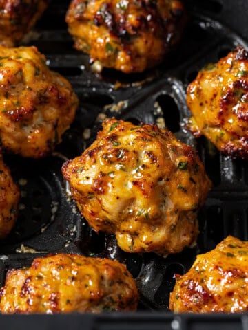 Juicy chicken meatballs in an air fryer basket.