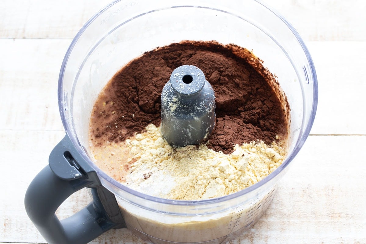 Lupin flour and cocoa powder added on top of wet ingredients in the food processor bowl.