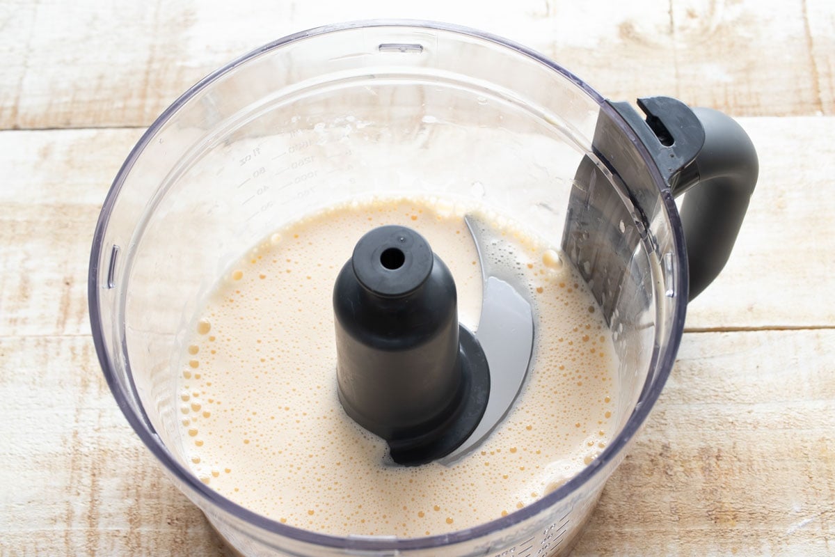 Frothy blended eggs in a food processor bowl.