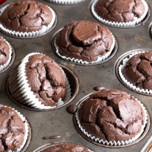 Baked Chocolate protein muffins in white muffin cups in the muffin pan.