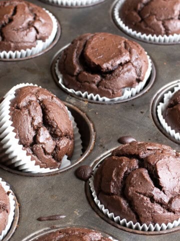 Baked Chocolate protein muffins in white muffin cups in the muffin pan.