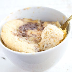 A coconut flour mug cake in a mug and a spoon.