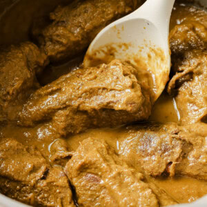 Beef rouladen in a thick gravy and a spoon.