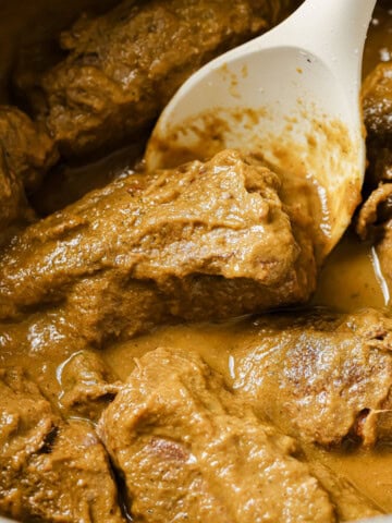 Beef rouladen in a thick gravy and a spoon.