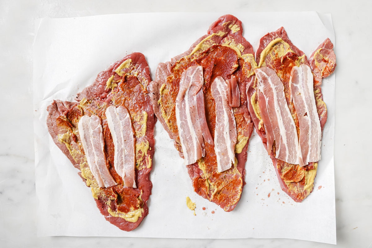 THin beef strips topped with mustard and tomato paste plus two strips of bacon.