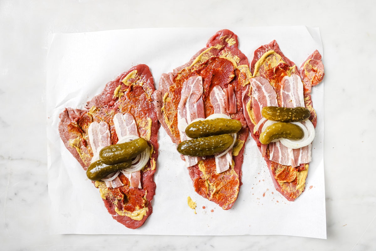 Adding halved gherkins onto the prepared beef strips.