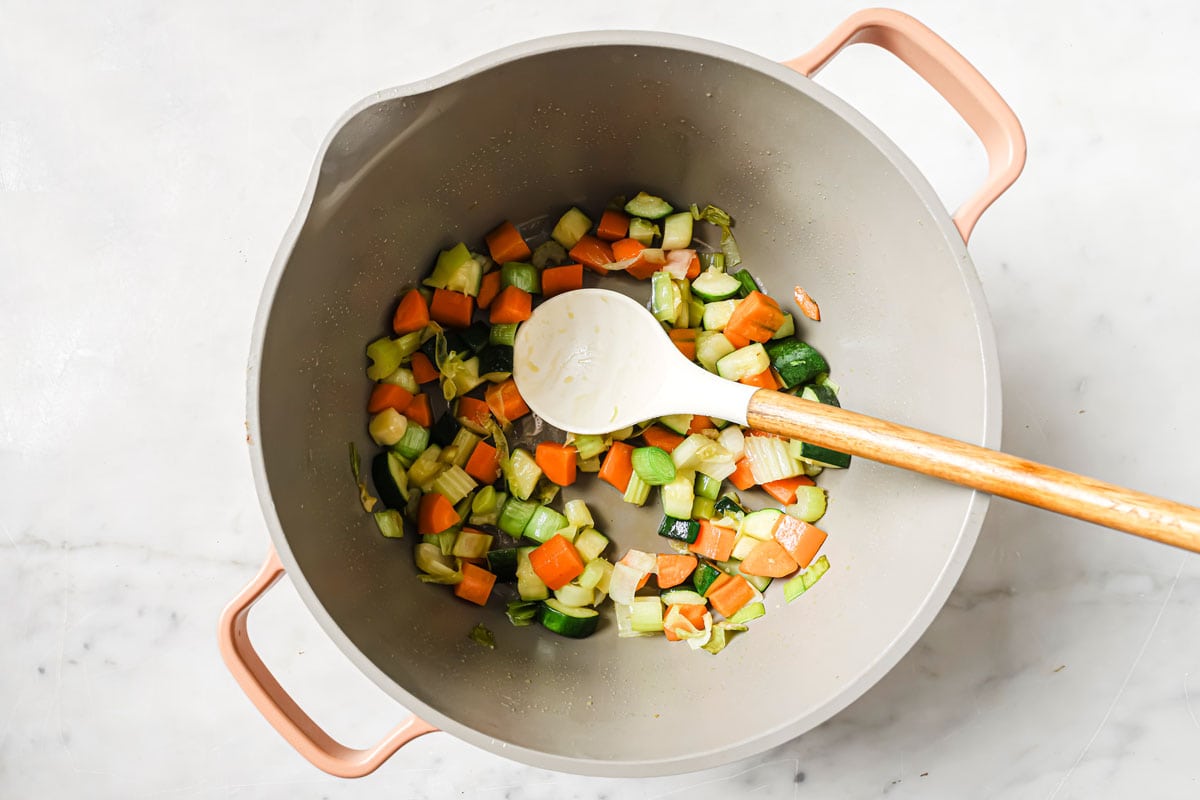 Sauteing chopped vegetables in a pot.