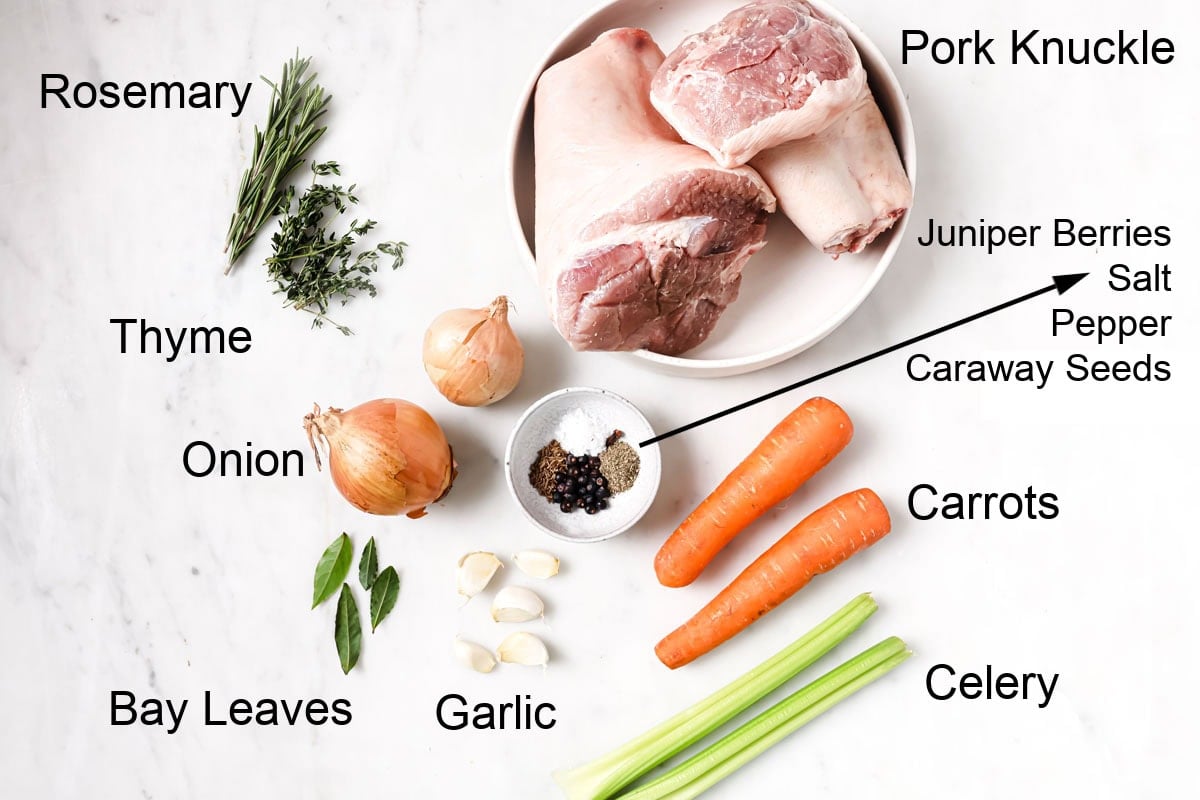 Ingredients to make German pork knuckle - 2 pork knuckles and vegetables and herbs and spices for the sauce, measured and labelled.