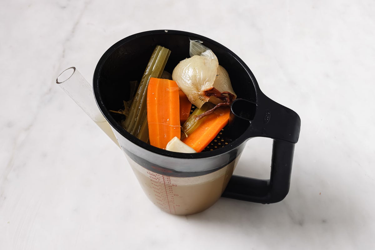 Cooked vegetables in a straining pot with pork broth.