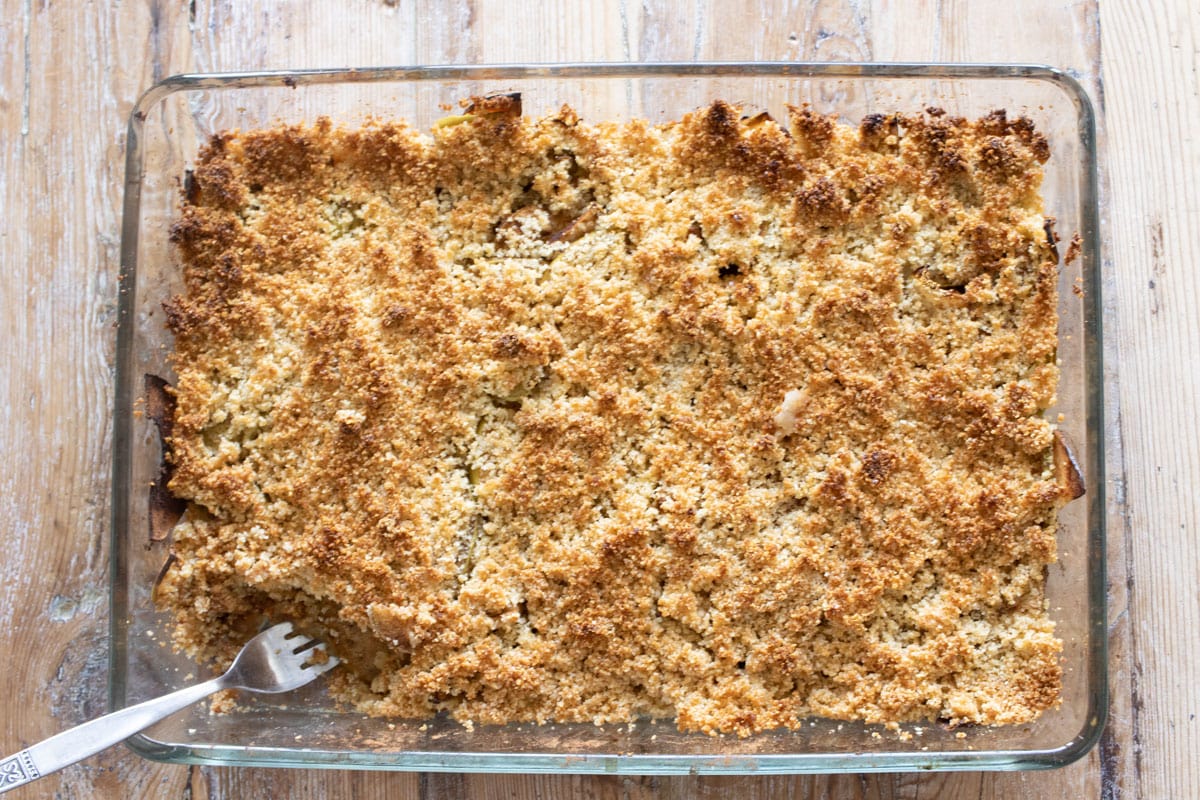 Apple crumble baked in a casserole baking dish with a fork.