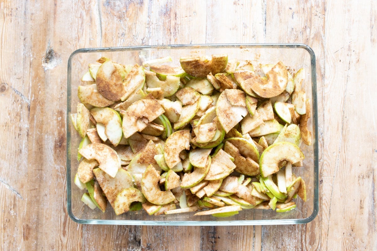 Apple slices tossed in spices and sweetener in the baking dish.