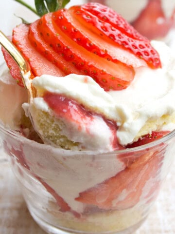 Sugar free trifle with strawberries in a cup and a spoon.