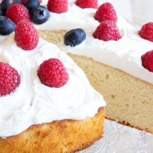 A slice of keto almond flour cake with a mascarpone frosting and berries being removed from the cake.