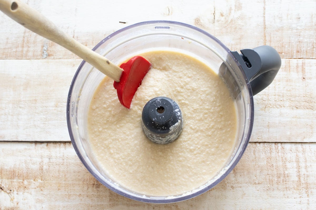 Almond flour cake batter in the food processor bowl and a spatula.