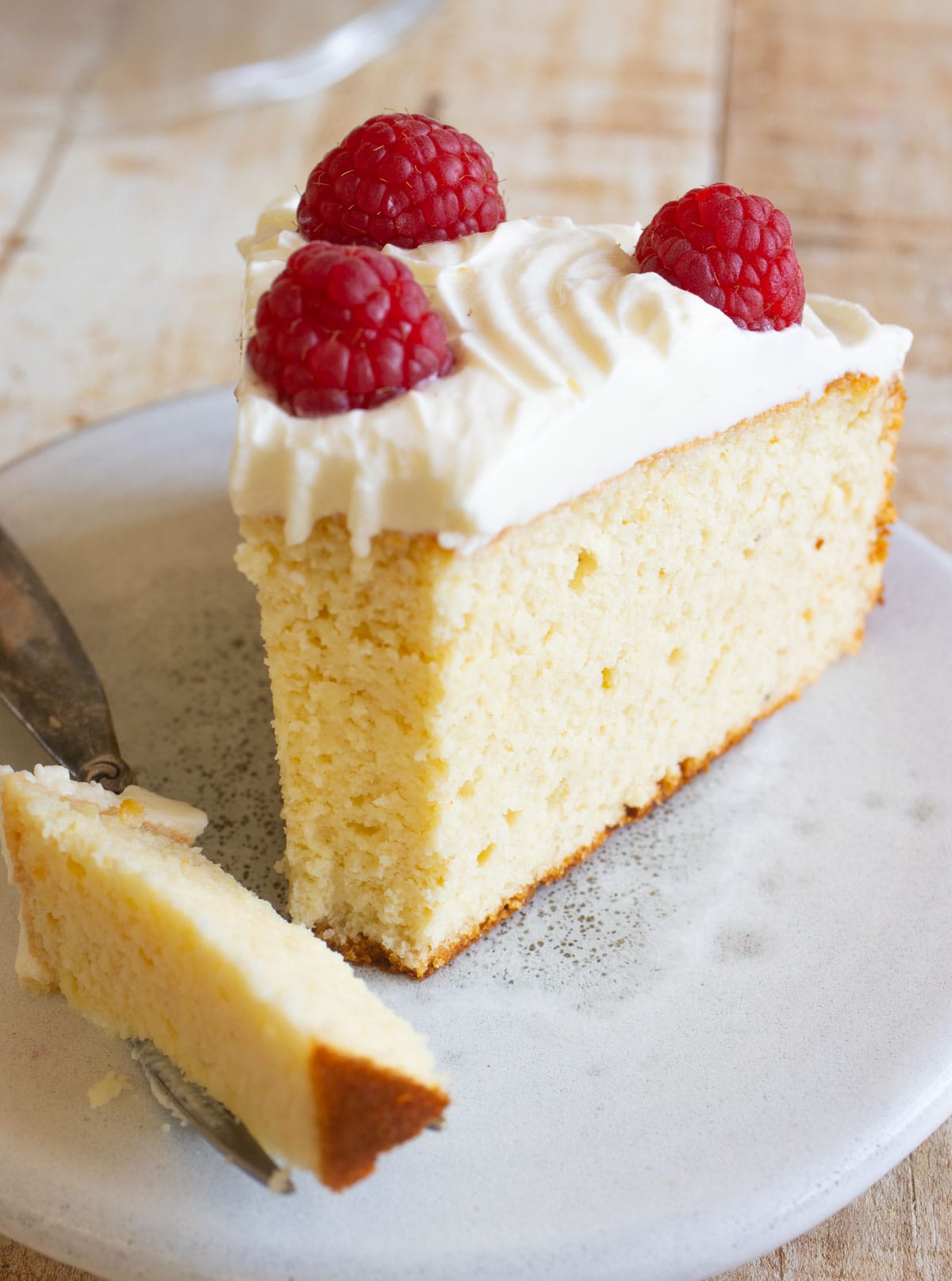 A slice of sugar free almond flour cake with frosting and berries.