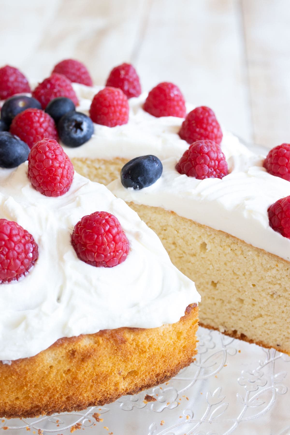 Almond flour cake topped with mascarpone frosting, raspberries and blueberries.