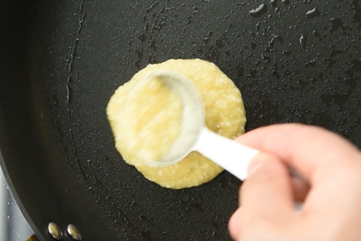 Spooning coconut flour pancake batter into the pan.