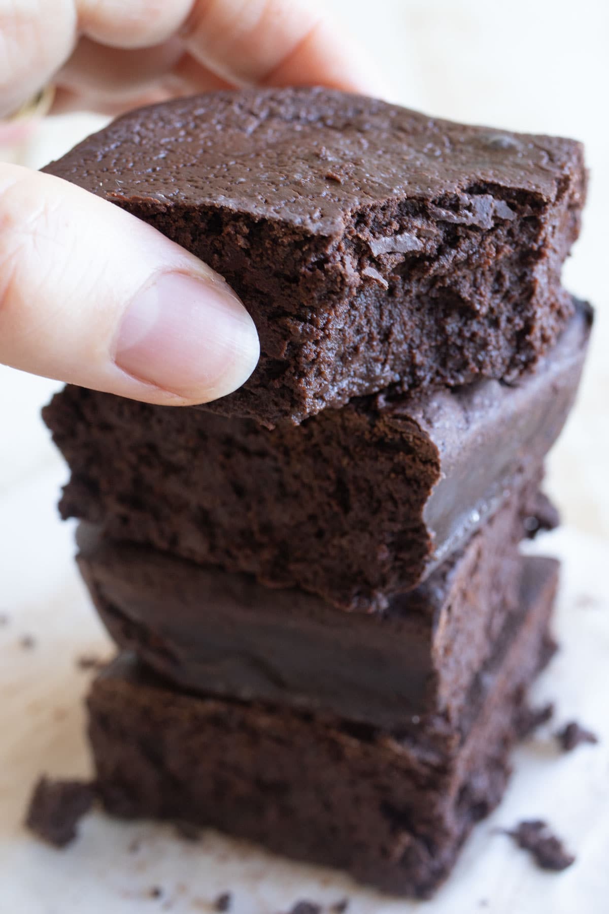 Hand lifting a cottage cheese brownie from a brownie stack.