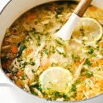 Greek lemon chicken soup with cauliflower rice in a pot and a spoon.