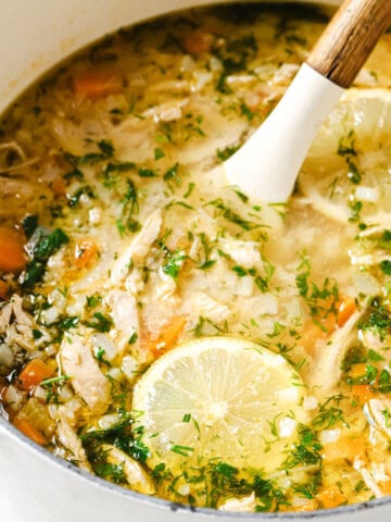 Greek lemon chicken soup with cauliflower rice in a pot and a spoon.