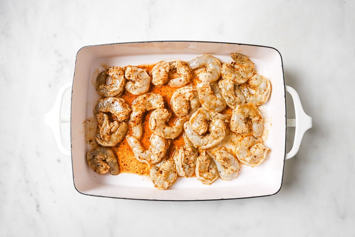 Raw marinated shrimp in a casserole dish.