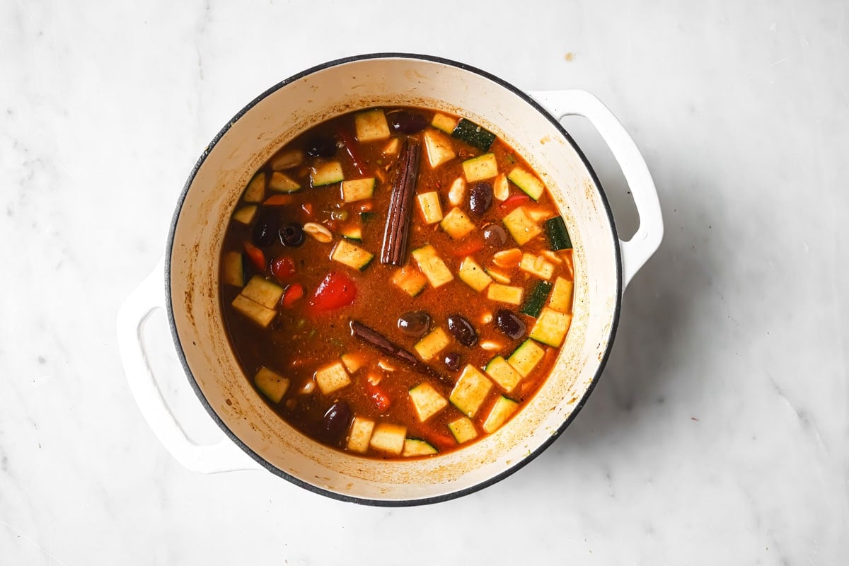 Adding the broth to the vegetable and lam mixture.