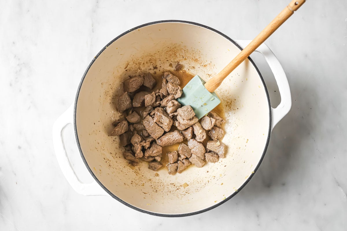 Frying cubed lamb in a large pan.