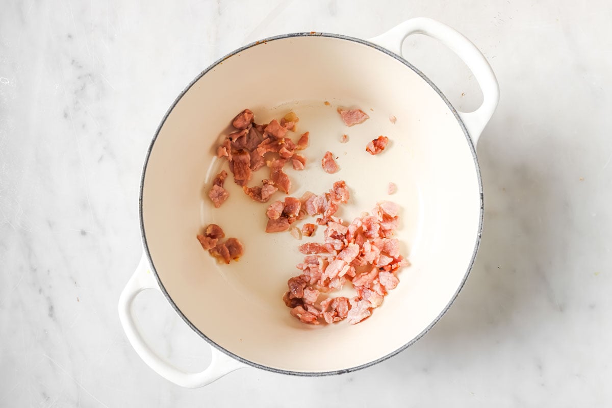 Browning chopped bacon in a pot.