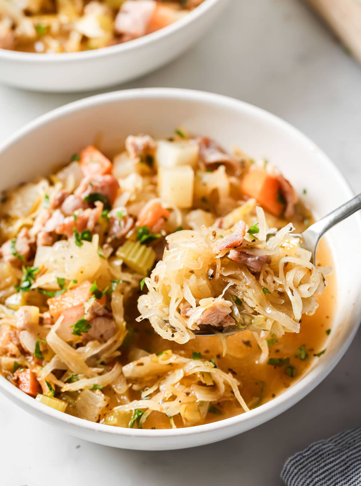 A serving bowl with sauerkraut soup and a spoon.