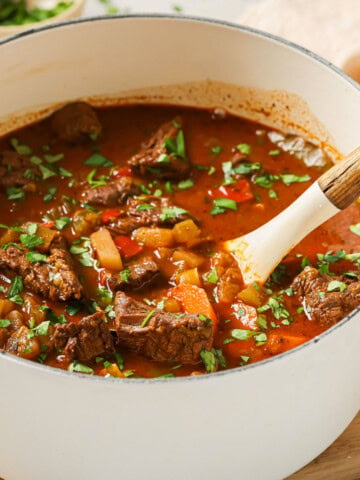 Goulash soup in a pot topped with parsley.